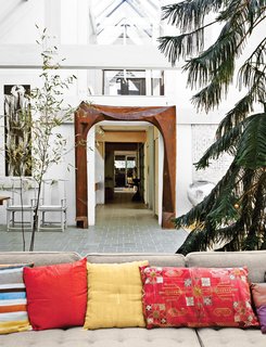 Living room highlights include a carved chestnut archway by Wharton Esherick, a 1949 Edward Wormley sofa for Dunbar, and a Norfolk pine tree.
