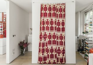 A handwoven silk ikat print, which Molineus acquired in Uzbekistan, is draped between the kitchen entrances. A Sapiens bookshelf by Bruno Rainaldi stands at far right.