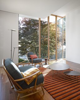 The flooring throughout the interior is maple. A vintage Ercol sofa and arm chair, Eclipse coffee table by Stua, Wide Wale rug by Bev Hisey Textile Design, and Moon floor lamp by Estiluz Spain furnish the living room. "Extensive planning went into 'aging in place' forecasting a host of different scenarios about what that meant physically and psychologically," Tedesco says. "We did 'day in the life' modeling to understand all the various barrier free requirements that might arise. This heavily influenced the design of the house especially in the flow of circulation and the size of specific elements including the corridors, door widths, washrooms (showers, sinks and toilets design and location) and bedrooms. Finally the entry sequence from the driveway and the walkway to the front and side doors were designed to be future proofed to allow aging in place."