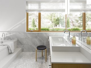 Carrara marble clads the spacious bathroom.