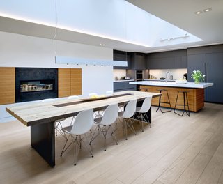 The kitchen also displays a reliance on natural materials and soft colors. For the wine storage area, Roundabout Studio used reclaimed wood from the original building. The new dining room table also utilizes repurposed studs salvaged from the building’s demolition. The kitchen stools are from Avenue Road, the dining room table is custom, and the pendant light is from Dark Tools.