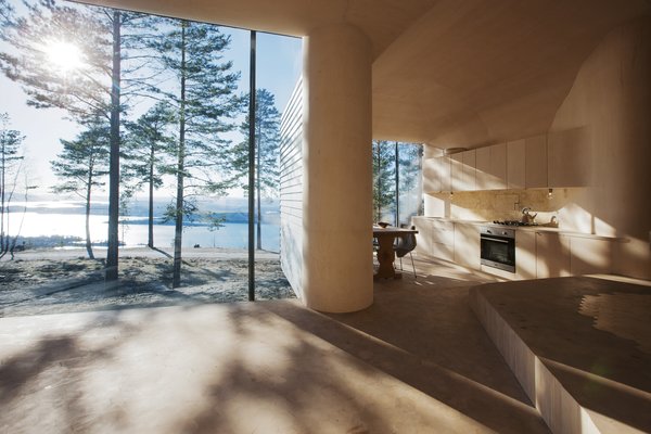 The architects designed the large glass expanses in the dining and living areas so that their frames are hidden from view. “I love the way the light comes into the cabin and meets the curved surfaces of the walls and ceilings,” Bae Brandtzæg says. The kitchen’s custom cabinets were designed by Atelier Oslo and constructed by the contractor, Byggmester Bård Bredesen. The gas-powered stove, oven, and fridge are by VERA. Photo 4 of Cabin Norderhov modern home