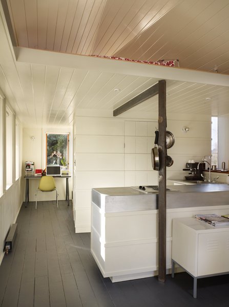 Tiny 1920s Garage Transformed Into a Charming Studio - Photo 6 of 8 - A utilitarian core contains the kitchen, bathroom, closet, and loft ladder. The kitchen’s walls are clad with recycled wooden boards trimmed with horizontal battens that hide the oven and refrigerator from view.