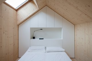 Each bedroom is designed to replicated a mini house, and follows the roof's pitch. A skylight lets in light. A custom unit made of white-painted MDF panels provides necessary storage.