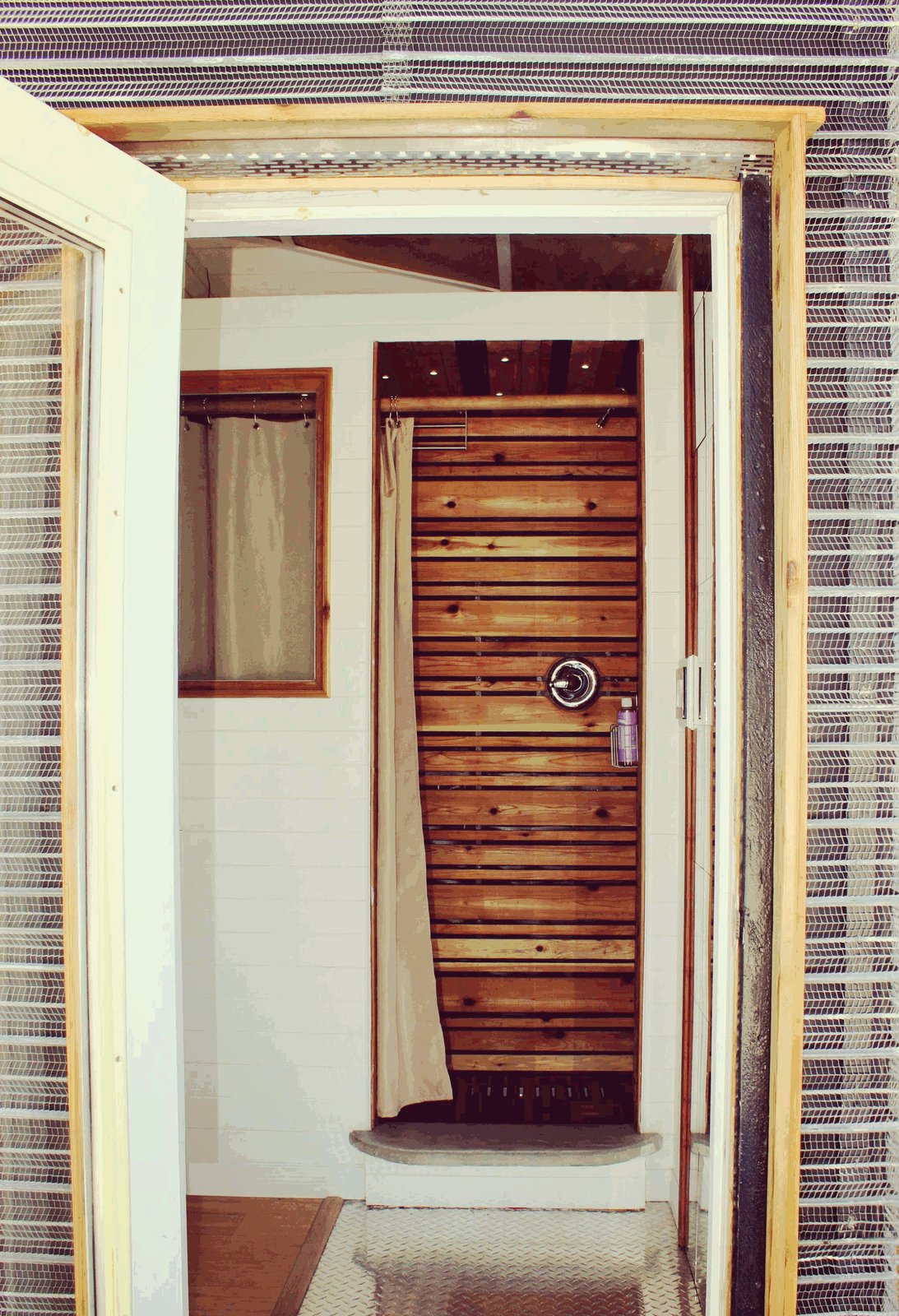 The shower, as seen through the main entrance. The metal-mesh open-joint rain screen is designed to rust over time.