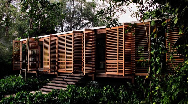 Lightweight shuttered doors made of western red cedar line the outer edge of the front porch, providing privacy and protection from the weather. The wood is left unstained, so it will age naturally in a way that’s similar to the surrounding ipe wood. Just behind the shutter system, 50-feet of glass walls broken into four sets of sliding panels open to eliminate the barriers between indoor and outdoor spaces. Photo 2 of Brillhart House modern home