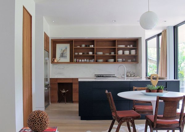 For the kitchen, American cherry wood was used to create cabinets that establish a warm and sturdy tone. Each piece of lumber was purchased at auction by the Brillharts and stored in New Hampshire, before being shipped to Miami and milled on site. The wood island is painted black to provide a point of visual contrast. Photo 4 of Brillhart House modern home