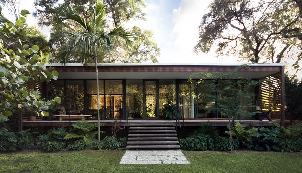 Between the front and rear exteriors, over 800-square-feet of patio space extend the living areas into the outdoors. From this angle, the references to Florida cracker architecture are obvious. The sleeping quarters are connected via a central corridor and kitchen to the living space on the other end of the building, a modern interpretation of the classic dogtrot house. Photo 8 of Brillhart House modern home