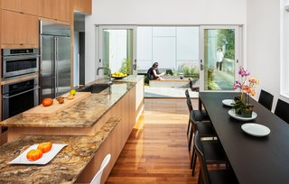 To adhere to a limited budget, Höweler + Yoon used basic materials throughout—slate, concrete, wood, cement board—but splurged on a marble countertop in the kitchen. "Because the house and millwork was so neutral to room could take a bit more richness," says Yoon. From within the combined living/kitchen/dining area, one only sees the microcourtyard outside.