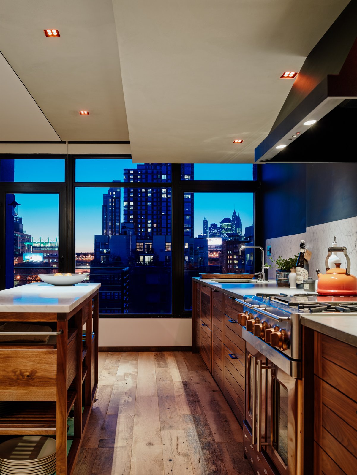 A large kitchen island makes up for the lack of upper cabinet space and separates the kitchen from the living room. The cabinetry is custom made by Henrybuilt, hidding all appliances other than the copper BlueStar range.