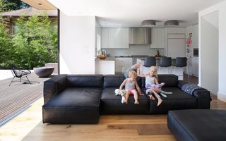 The addition of a living room beside the kitchen lets mom and dad spend more time with their kids – and watch over their activities. The children are sitting on a NeoWall couch by Living Divani, the light fixtures above the island are Smithfield by Flos, and the floor is oak.