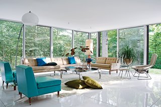 The spacious living room, filled with vintage furnishings by Harry Bertoia, Paul McCobb, overlooks the heavily wooded site, which adjoins a protected watershed. Photo by: Jason Schmidt