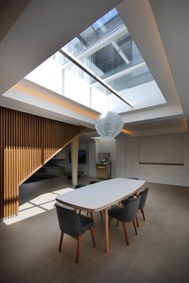 10 Dwell-Approved, New-Old Homes in the UK - Photo 2 of 18 - In the dining room, a James Burleigh table sits beneath a sizeable skylight. Throughout the ground floor, additional lighting is recessed in the coffered ceilings. Painted brick walls provide a reminder of the building’s industrial past.