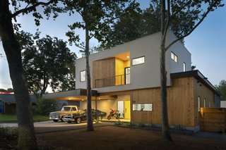 A Mighty Oak Tree Frames This Family Home in Austin - Photo 1 of 10 - The structure's white stucco second story nods to the architecture of traditional tree houses and is used as sleeping quarters for the owner’s children. The leaves of the central oak tree can be seen peaking out above the façade.