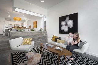 A Mighty Oak Tree Frames This Family Home in Austin - Photo 6 of 10 - The living room sits a few steps down from the kitchen-dining area, and is demarcated by a board-formed concrete planter. Occupants can gather in the Blu Dot sofa and chair. Amid the concrete and fabric, an Ikea coffee table provides a warm wooden touch.