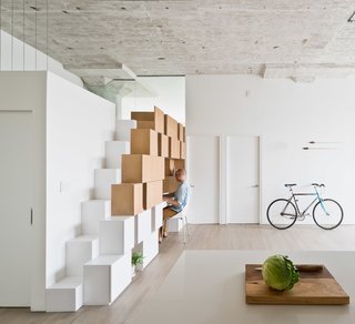 Brooklyn Loft Renovation Masters Storage With a Custom Cabinet Wall - Photo 3 of 10 - In the family room, cabinets open up to create an office desk. The steps on the left lead up to a mezzanine space that serves as play space for the children and a sleeping area for guests.