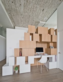 Brooklyn Loft Renovation Masters Storage With a Custom Cabinet Wall - Photo 4 of 10 - Gaps and openings between the handle-less, white oak shelves are functional and decorative, holding plants, books, and office supplies. Small touches, such as the matching color of the chair and the lower shelves, help accent the clean white surfaces.