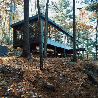 30 All-Black Exterior Modern Homes - Photo 18 of 30 - Torontonians Dan and Diane Molenaar head north to Drag Lake when they need a weekend away from urban life—though they brought some of the city with them. The mirrored windows that circle the cottage were recycled from two office towers in Toronto.
