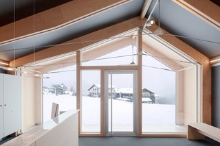 This Prefab Ski School in the Alps Took 10 Days to Assemble - Photo 3 of 7 - Girodo says the "high insulation performance of the shell" allows the building to function in a setting that experiences significant temperature fluctuations and extreme cold. Occupants of the front room, which functions as a reception area, can take in the views from its full-height windows in complete comfort.