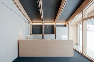 This Prefab Ski School in the Alps Took 10 Days to Assemble - Photo 4 of 7 - All of the interior furnishings were designed and built by LEAPfactory for this specific project. These pieces, including the reception desk, are made of laminated boards and the same reforested beech wood used in the school’s structure. A door behind the reception desk leads to a living room for the ski and snowboard instructors.
