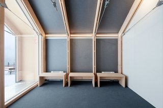 This Prefab Ski School in the Alps Took 10 Days to Assemble - Photo 5 of 7 - The building’s restrained color and material palettes carry over to the minimalist wood benches in the reception area. Since the facility must withstand heavy usage as well as inclement weather, it was built with "easy maintenance" in mind, according to Girodo.