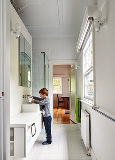This Transformed Melbourne House Resembles a Quirky Village - Photo 4 of 11 - In the main bathroom, Art Deco crown molding reminds residents of the house’s past. New fixtures include white laminate cabinets and sinks and faucets by Roger Seller.