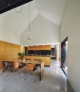 This Transformed Melbourne House Resembles a Quirky Village - Photo 6 of 11 - The dining room serves as the hub for all activity. Original Series 7 chairs by Arne Jacobsen complement a table Maynard designed and dubbed the "Zero Waste Table," since it utilizes every inch of a large wood sheet. To the right, a sliding door opens to the garden.