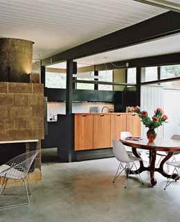 The duo added custom redwood cabinetry on the dining area side. The pendants are from Birchwood Lighting.