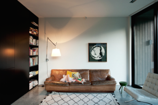 This Kid-Friendly Home is Full of Surprises - Photo 6 of 9 - The architect specifically chose a palette of natural finishes, including the polished concrete floor that flows the length and breadth of the ground level.<br><br>By way of contrast, the couple’s eclectic collection of much-loved vintage furniture, including Mies van der Rohe Barcelona chairs, an Artemide lamp, and this 50-year-old sofa by mid-century Swedish designer Arne Norell, provide color and warmth. "The bookcase also makes use of space to add layers of texture. Books are always a great addition to any interior," says Cooke.<br><br>The Beni Ouarain rug was purchased on a trip to Morocco.