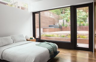 The master bedroom’s clerestory window provides morning light while allowing for privacy from the neighbors. The Siena bed is by Naoto Fukasawa for B&B Italia, the side table is Room & Board, and the globe light is vintage. The windows are by Fleetwood and the doors by Bonelli.