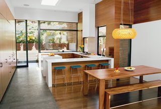 Bernstein specified sequenced walnut veneers in the kitchen and dining area and counters from Caesarstone. The Chrysalis bar stool is by One & Co for Council. A Foscarini pendant hangs above Ligne Roset’s Eaton table and bench.