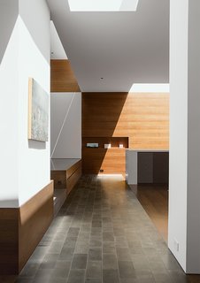 Because the residents wanted lighting "to fade away," the home makes the most of natural light and minimizes fixtures. Each room has two sources of daylight, usually in the form of floor-to-ceiling windows and skylights. Fluorescent lights integrate into the surface of the skylights so they don’t protrude into the space.