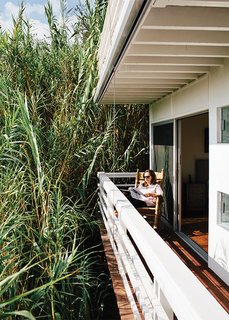 A Midcentury Home Enjoys Views from Every Angle - Photo 12 of 14 - Marjorie takes to a Brumby rocking chair on the deck off the bedroom, which is privatized by a forest of bamboo.