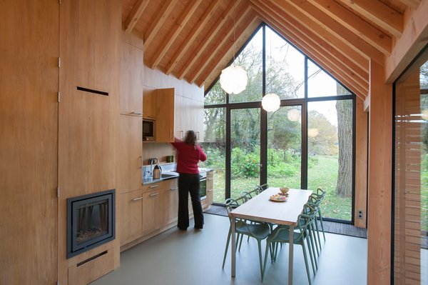 Fine wood craftsmanship defines the dwelling's interior, where all the facilities—from the kitchen cabinets to the fireplace to the bathroom—are integrated into a single oak wall, handmade by van Norel. He also made the dining table, which is paired with Philippe Starck master chairs—the only ready-made items in the space other than fixtures and appliances. Photo 6 of Utrecht Cabin modern home