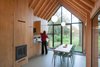 Fine wood craftsmanship defines the dwelling's interior, where all the facilities—from the kitchen cabinets to the fireplace to the bathroom—are integrated into a single oak wall, handmade by van Norel. He also made the dining table, which is paired with Philippe Starck master chairs—the only ready-made items in the space other than fixtures and appliances. Photo 6 of Utrecht Cabin modern home
