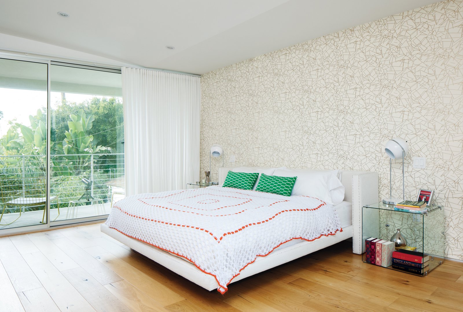 The master bedroom features wallpaper by Erika Wakerly. The glass tables next to the Croft House bed were gifts.