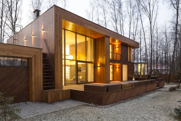 The house has two distinct volumes. The smaller one contains the garage, as well as the heating and air conditioning units, and is topped by a green roof garden accessible by an outdoor staircase. The larger, two-level volume sits slightly above ground and contains the living, dining, and sleeping spaces—all with windows facing east into the forest. Photo 3 of House in Moscow modern home