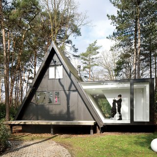 30 All-Black Exterior Modern Homes - Photo 2 of 30 - For this tiny house in the Belgian forest, a little extra square footage comes in the form of a glassed-in addition with a stellar view.