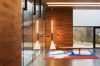 Holl designed seven rugs specifically for the home. The one in this room shows the building’s interplay of structure and water; the architect also designed the light fixture next to it.