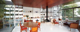 A structural steel wall in the living area doubles as a built-in bookcase. The side chairs, floor lamps, and dining chairs were salvaged from the Hotel Crillón in Lima. The daybed and coffee table were designed by Maria Eugenia Alvarez-Calderón, who helped Irzio and Lisette with the interiors. The fireplace is from Fireorb and, as throughout, the floor is poured white acrylic by Química Suiza.