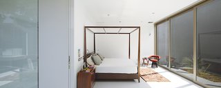 In the master bedroom is a four-poster bed by Javier Rubio and a vintage Warren Platner chair.