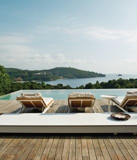 Made from white aluminum and oiled teak, the wooden sun loungers are from Viteo’s Pure collection. The long low table is made of Corian by DuPont and comes from the same line of outdoor furniture.