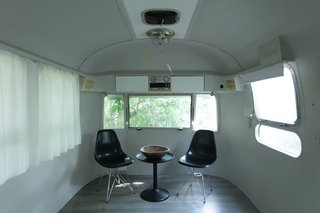 8 Ways to Renovate an Airstream - Photo 5 of 8 - The egg-like living room doubles as the children’s bedroom after dark, thanks to mattresses stored in a custom banquette in the studio area. The sole decorative elements are Eames shell chairs, an Ikea table, and a balsa-like children’s mobile received as a gift.