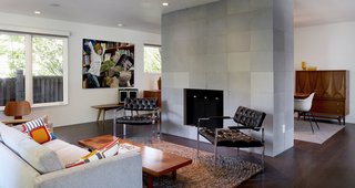 Renovating a Modern House in a Historic District - Photo 2 of 6 - The new living room is open and bright. A hearth sheathed in concrete tile from Sadlerstone—a material that recurrs throughout the interior—is the space's focal point. Much of the vintage furniture came from Retro Inferno.