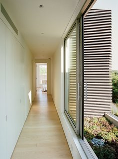 The structure blends into the site’s informal English-style garden, complemented with native coastal plantings by landscape designer Paula Hayes. Accessed by sliding doors, a second-floor garden is filled with a bed of low-maintenance, drought-tolerant sedum.