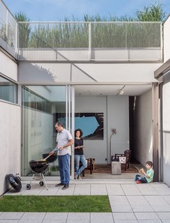 A Rooftop Garden Completes This Urban Pastoral Home - Photo 5 of 11 - The home’s enclosed courtyard sits at "the heart of the structure," says Baumann, who resides with his wife, Lisa Sardinas, and eight-year-old son, Oskar. "This is clearly the dominant space; everything flexes towards it." Baumann cast the square concrete floor tiles himself, enlisting the help of his son. A small, neat patch of grass—a playful nod to the archetypal domestic lawn—is edited down to a charming folly.