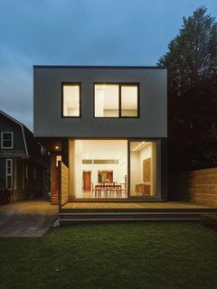 Thinking About Building a House? - Photo 3 of 4 - Light illuminates the back of the home at night. The Vicenza flamed basalt exterior and floor-to-ceiling windows are a bold counterpoint to the house's more traditional neighbors.