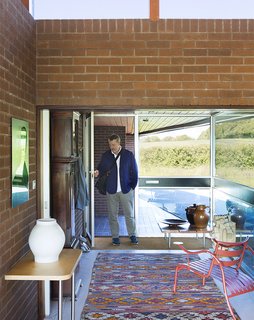 Quirky 1970s House in the English Countryside Showcases an Amazing Modern Furniture Collection - Photo 2 of 18 - Coakley commutes an hour into London, where his two SCP stores are located. In the entryway, a pair of Jasper Morrison tables join a vintage Moroccan rug. The circa 1980s Thinking Man’s Chair, also by Morrison, is in the foreground.