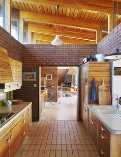 Quirky 1970s House in the English Countryside Showcases an Amazing Modern Furniture Collection - Photo 6 of 18 - The mahogany-paneled Poggenpohl kitchen system is original to the house. The kitchen opens to the living and dining area.