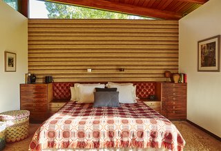 Quirky 1970s House in the English Countryside Showcases an Amazing Modern Furniture Collection - Photo 13 of 18 - The master bedroom boasts a 1970s tufted headboard from Heals Leather and a wall covering of burlap, wool and silk by David Hicks. The bed covering is vintage, 1950s, and the Blocks linen basket was designed by Donna Wilson and made by the People of the Sun, a nonprofit based in Malawi.